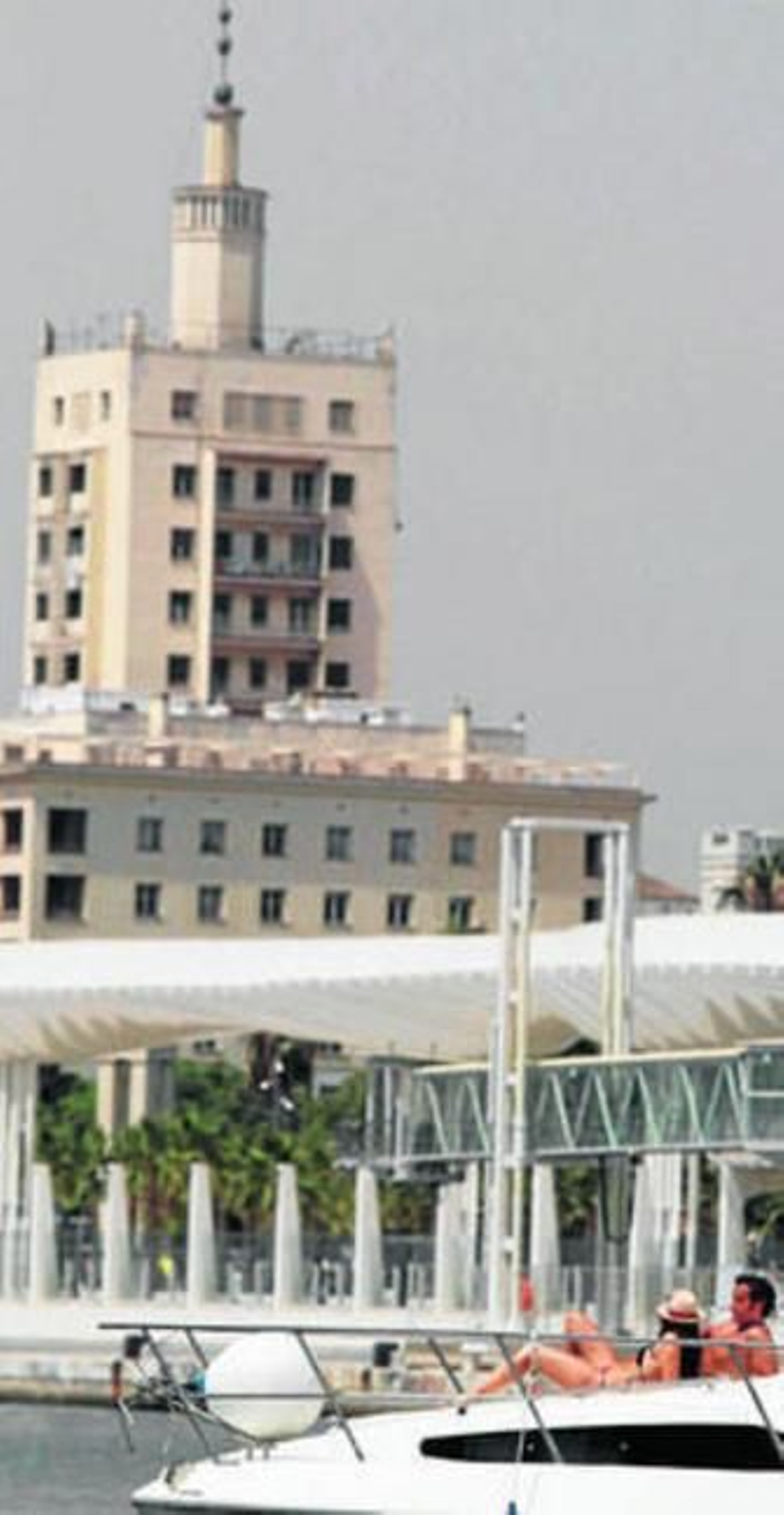 Dos personas toman el sol en un yate atracado en el puerto.