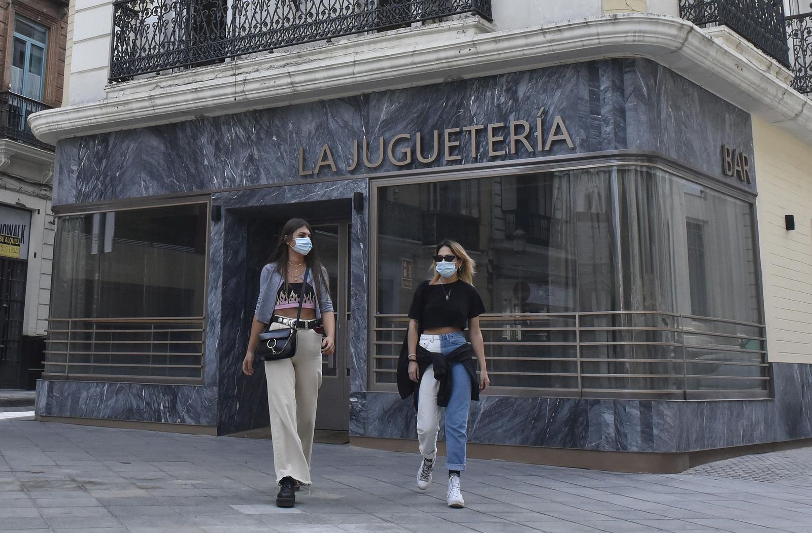 Dos jóvenes pasan junto a La Juguetería, bar de copas de la plaza de San Francisco esquina con la calle Hernando Colón.