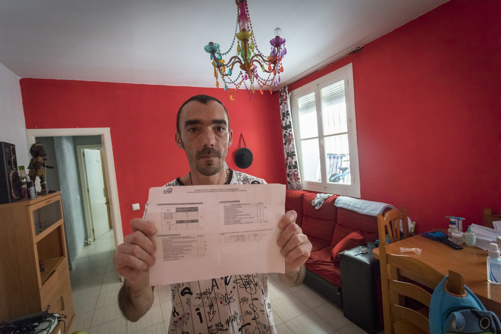 David Schneider muestra el baremo de Procasa con sus puntos en la casa en la que vive de alquiler con su familia.
