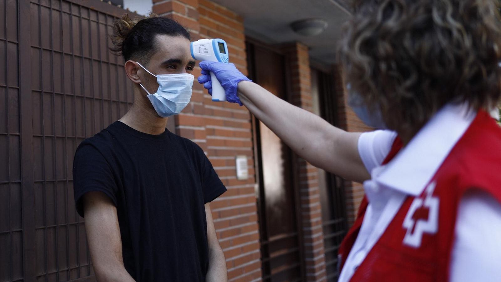 Una trabajadora de Cruz Roja mide la temperatura de uno de los inmigrantes.