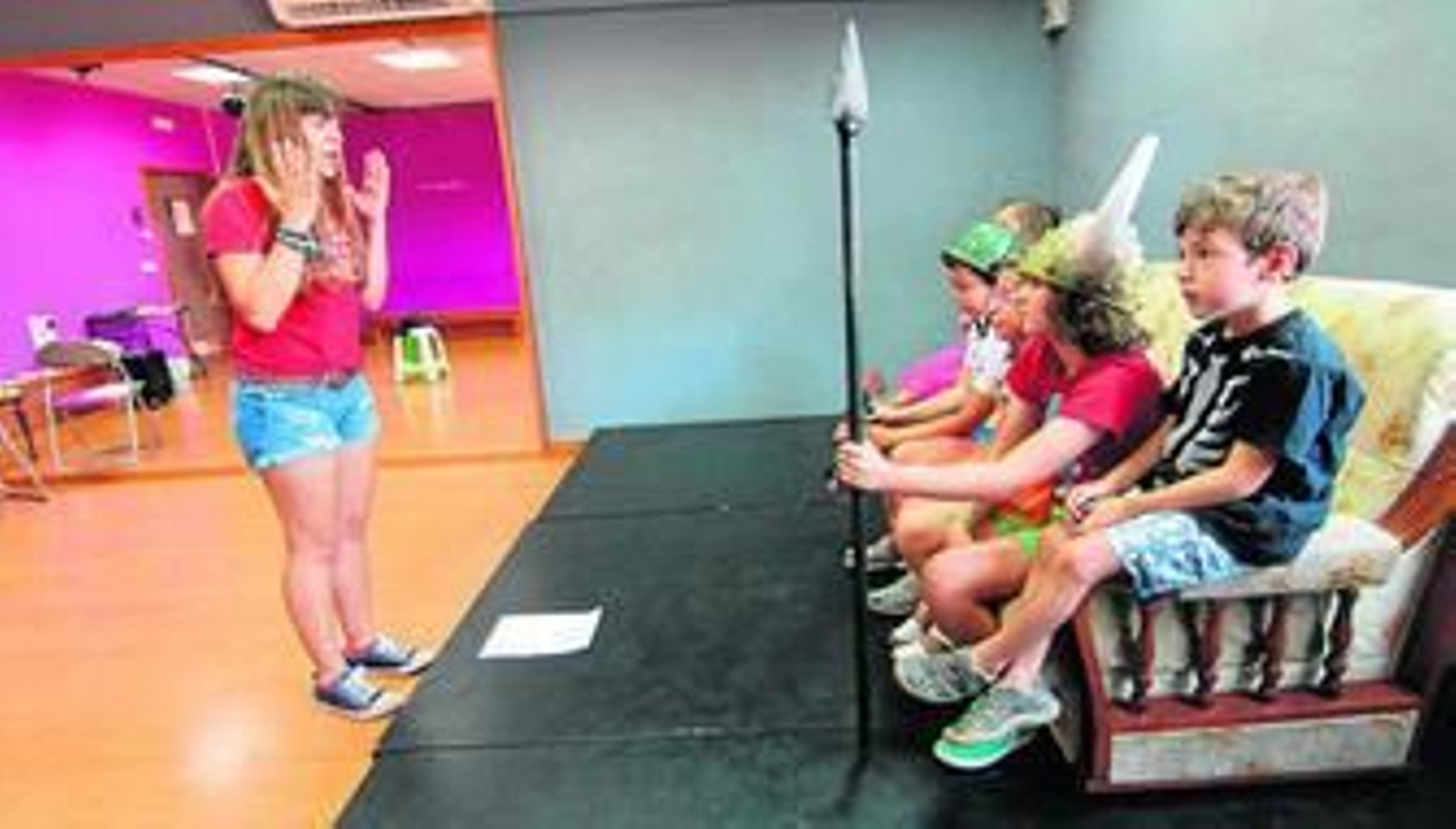 Un grupo de niños atiende a la profesora durante una clase de teatro.