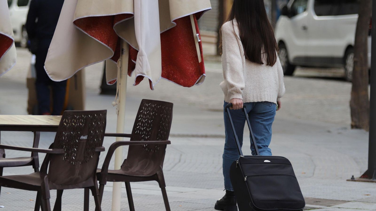 Una joven transita por el centro de la capital onubense con una maleta de viaje.
