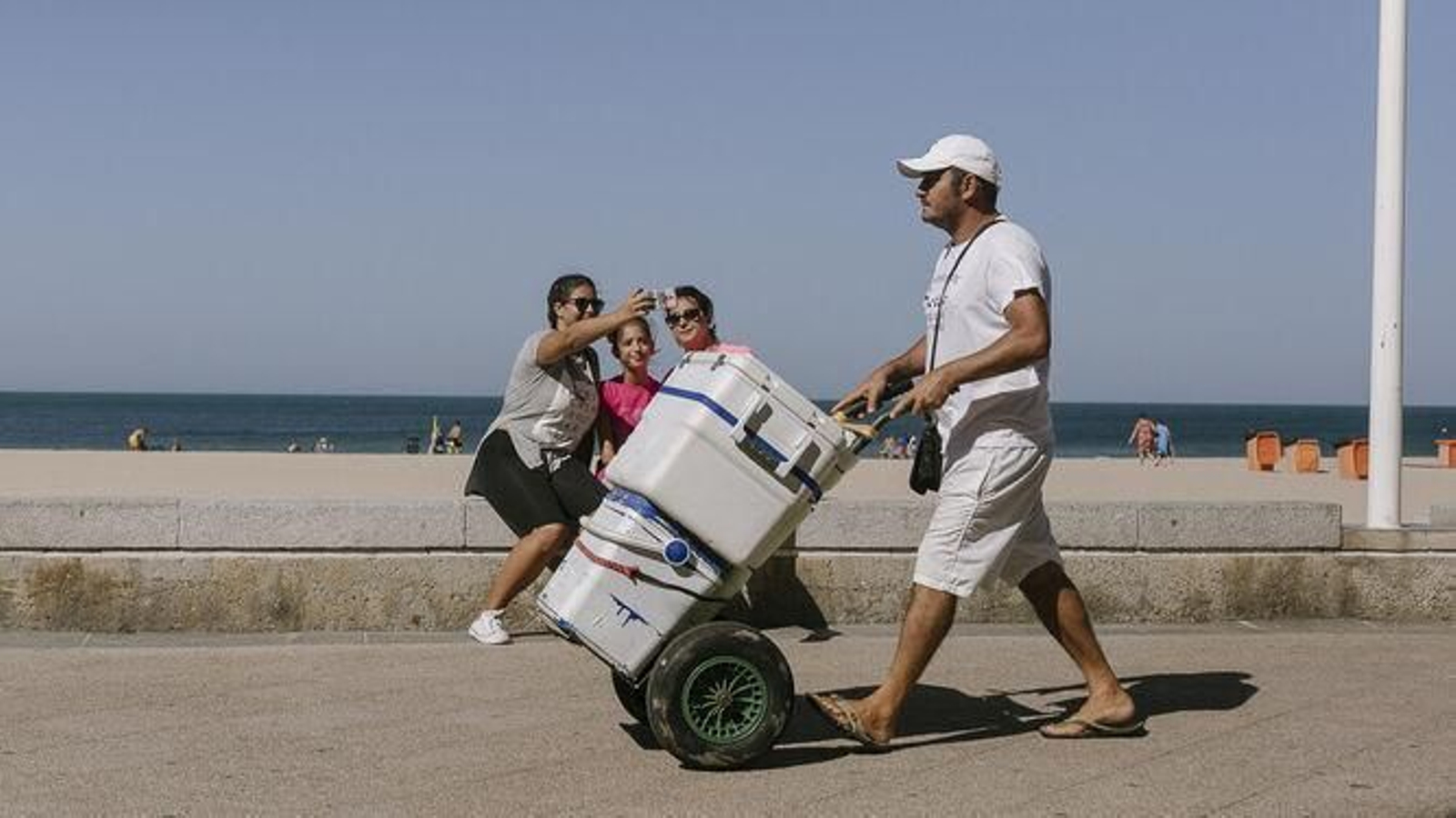 Un vendedor ambulante camino por el Paseo Marítimo antes de entrar a la playa.