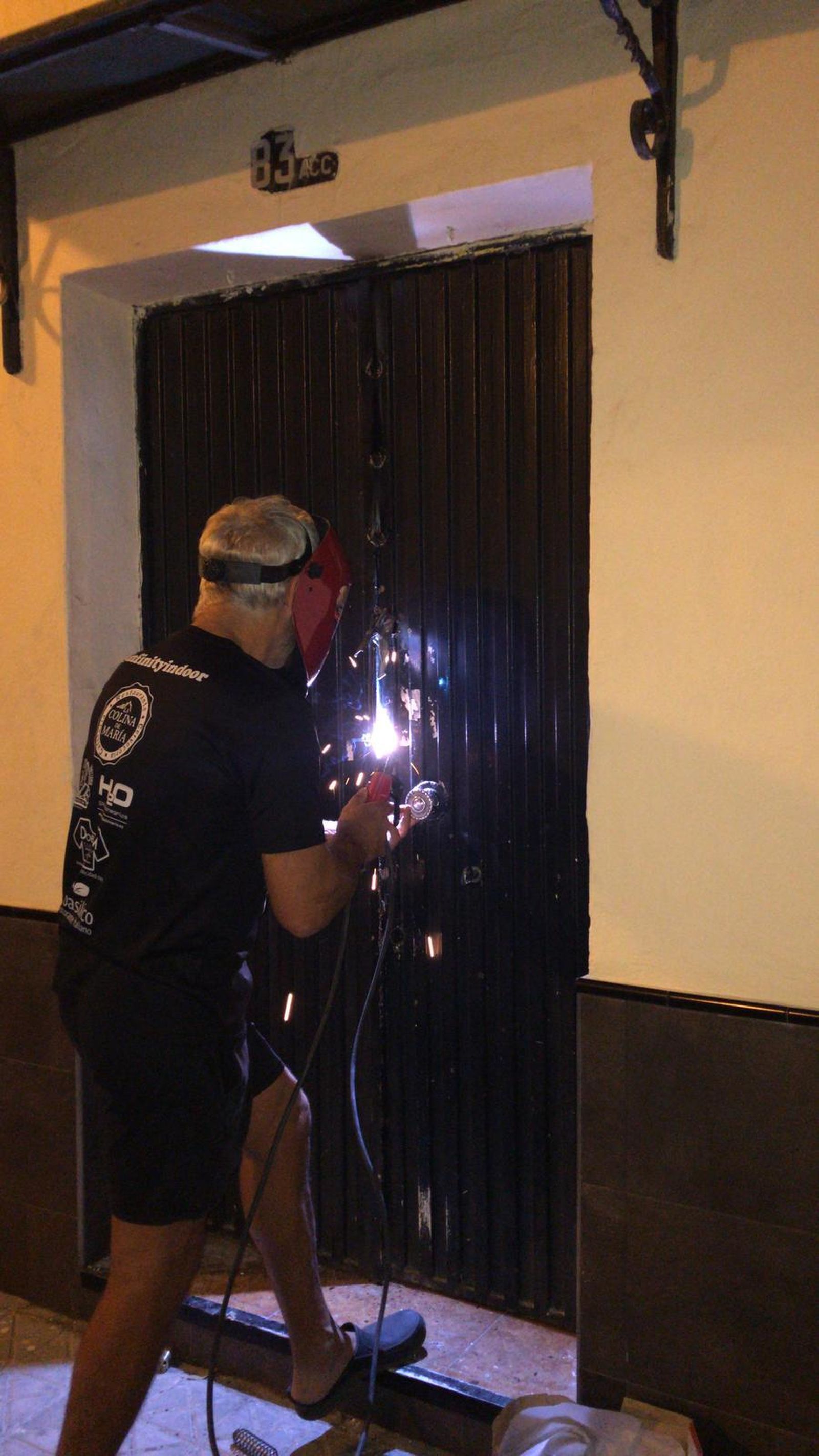 Un hombre suelda la puerta de la casa.