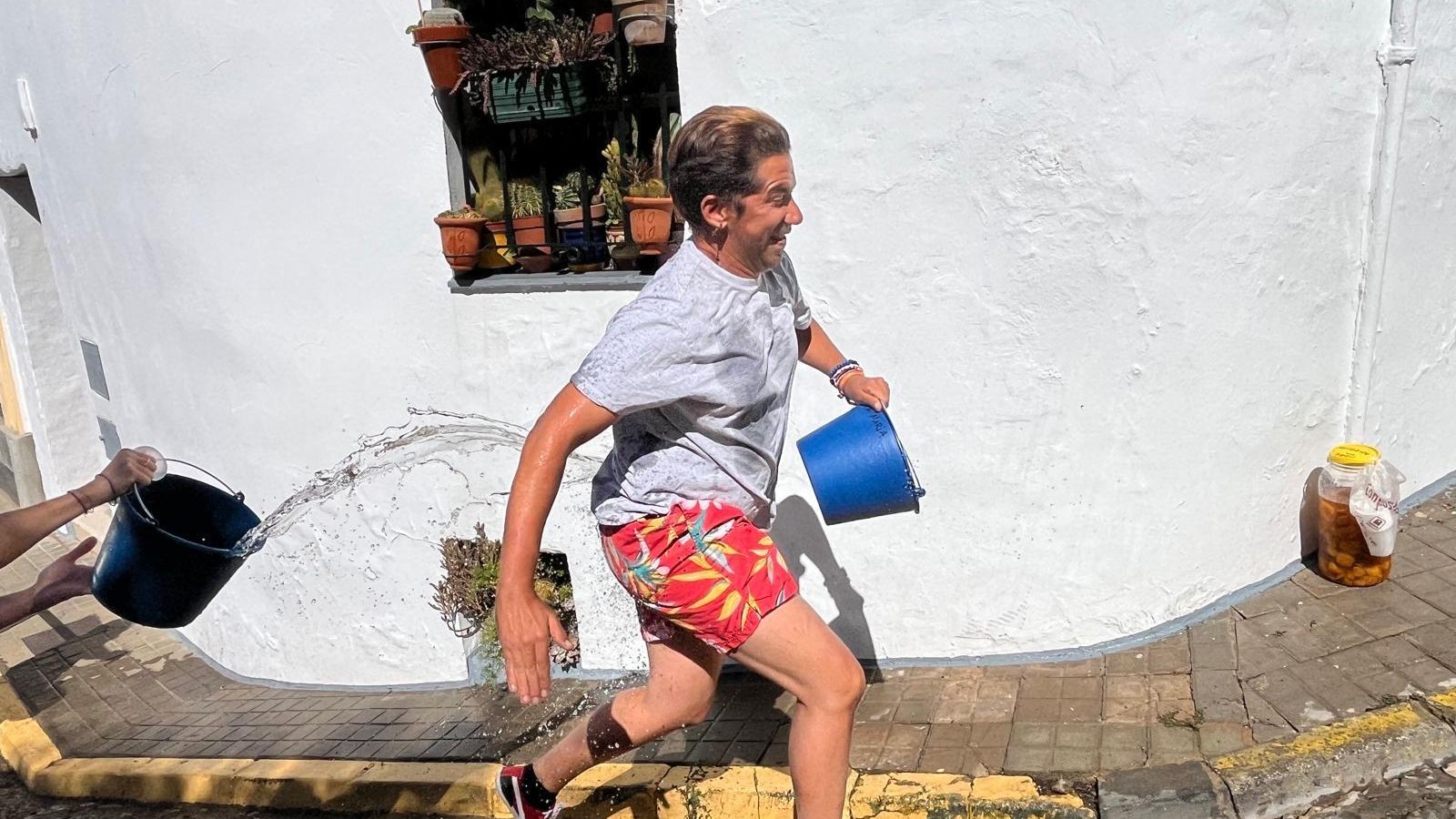 Momento en el que echan agua a una persona mientras corre por las fiestas de 'Los Jarritos'.