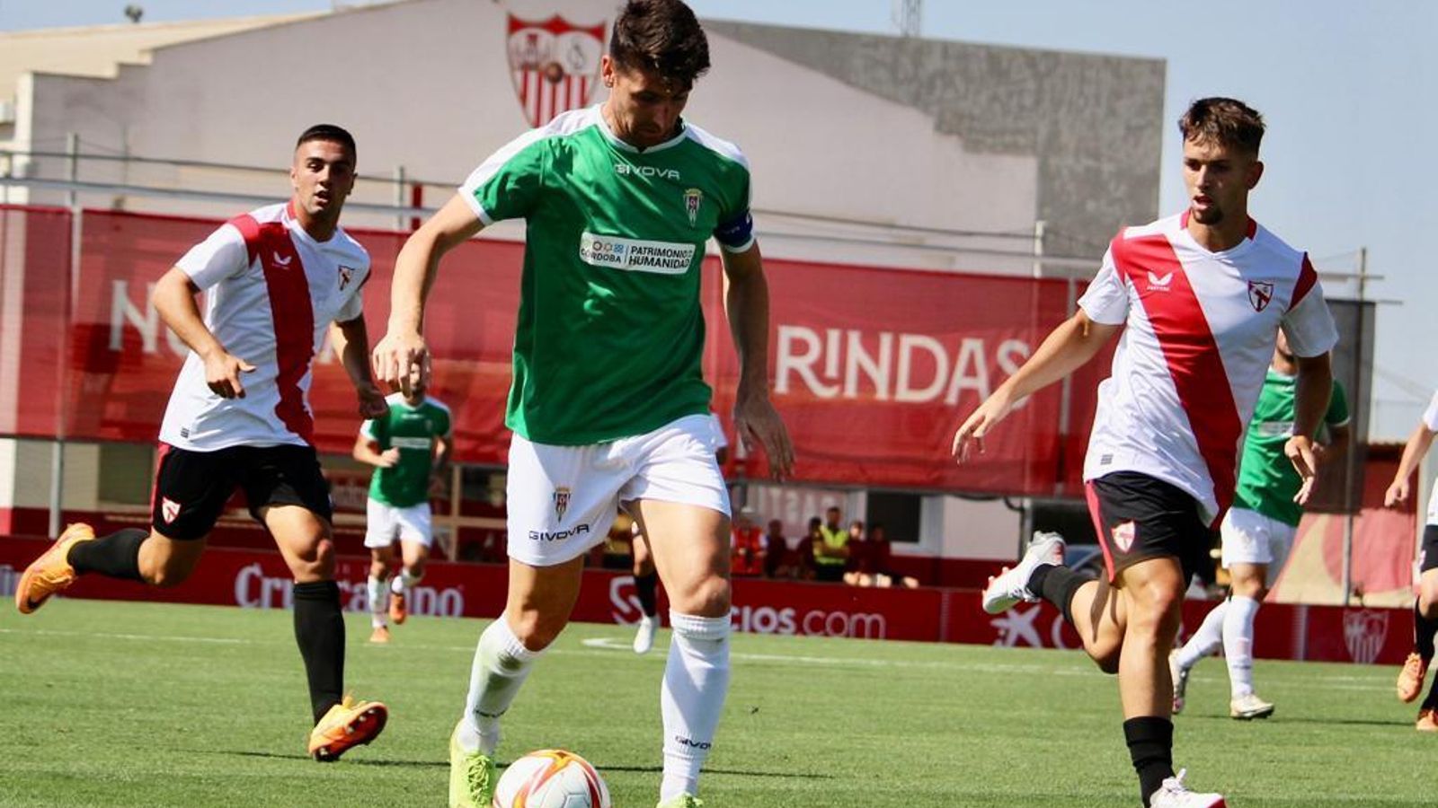 Javi Flores controla ante la presencia de dos jugadores del Sevilla Atlético.