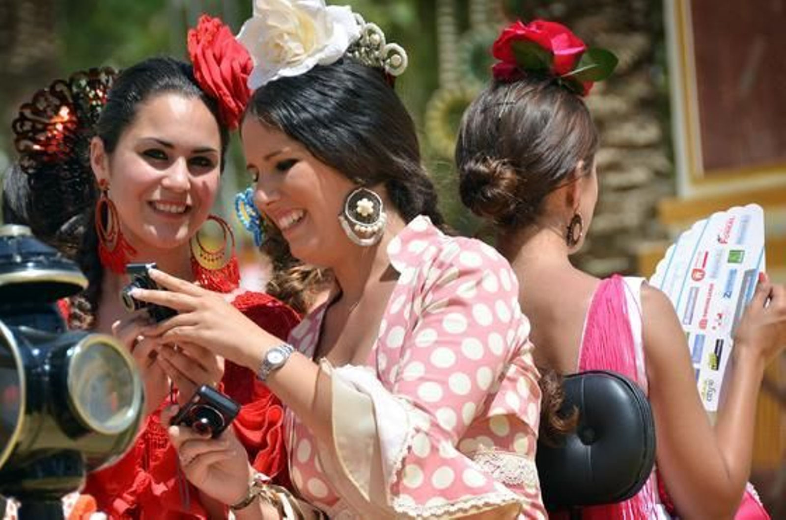 Calor y diversión. Dos jóvenes se divierten haciéndose fotografías en un coche de caballos mientras otra intenta refrescarse con un abanico.

Foto: Manuel Aranda