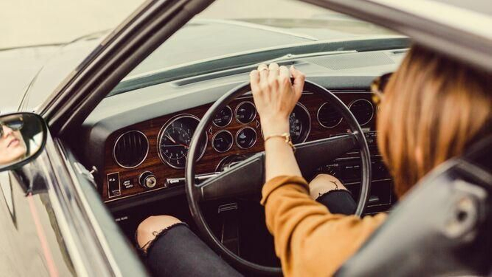 Una chica conduce su coche llevando gafas de sol