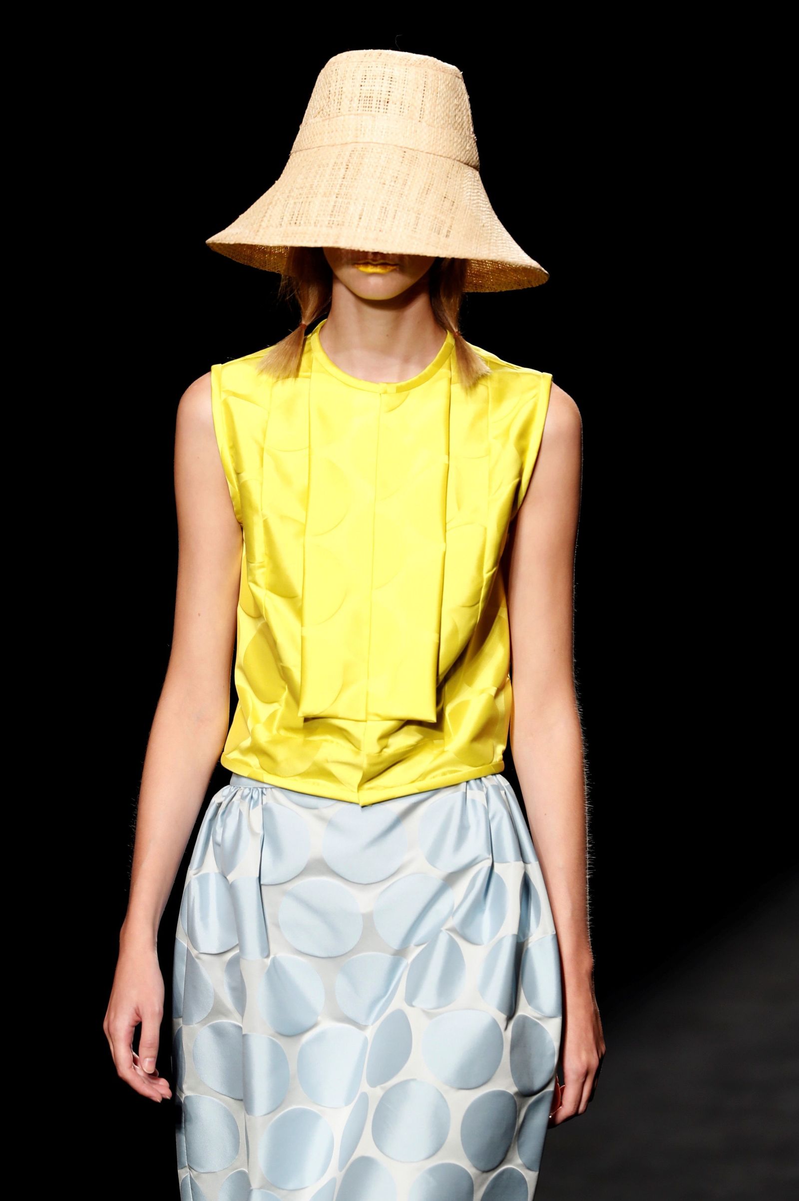 Modelo con la cara tapada y minimalista top amarillo con falda de lunares de Devota&Lomba.