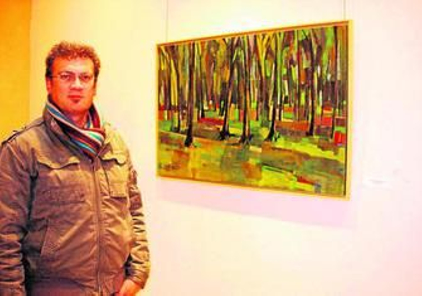 El pintor de Nerva, Joaquín Ramos, junto a una de las obras expuestas en el restaurante Rocataliata.