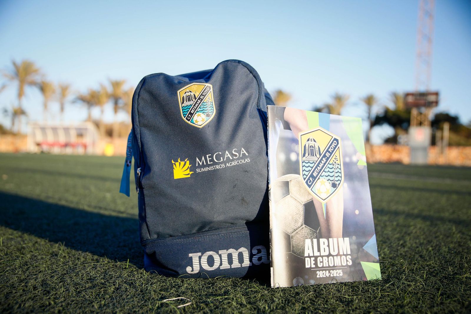 Portada del álbum de cromos del CF Retamar-El Toyo sobre el césped de las instalaciones deportivas de la barriada almeriense.