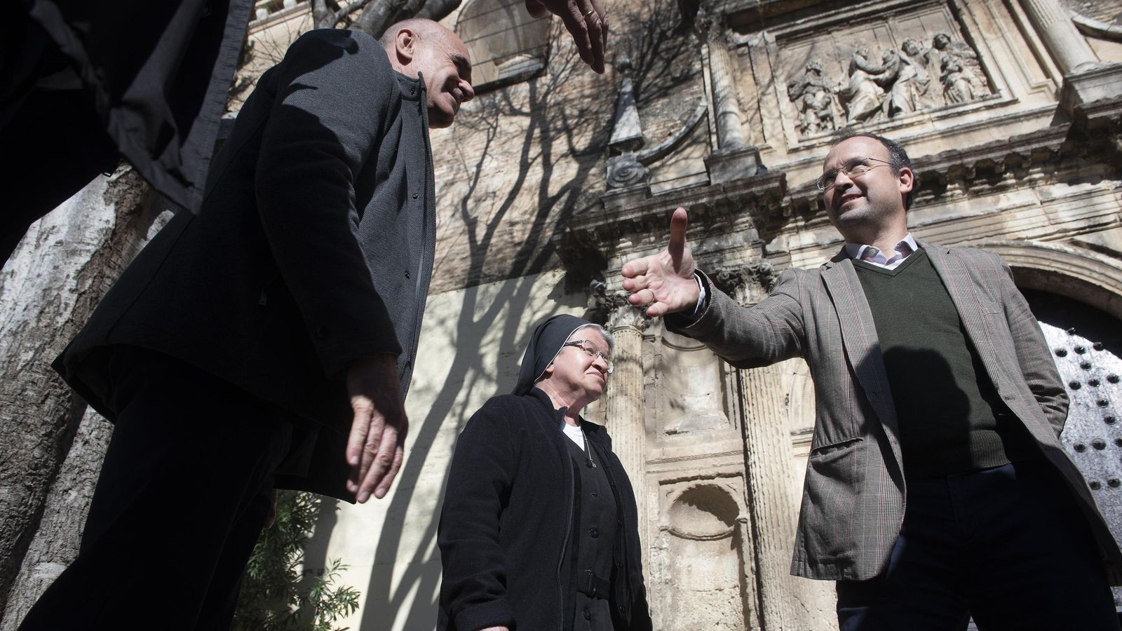 El alcalde saluda a las religiosas y los representantes de la comunidad con la fantástica portada al fondo.