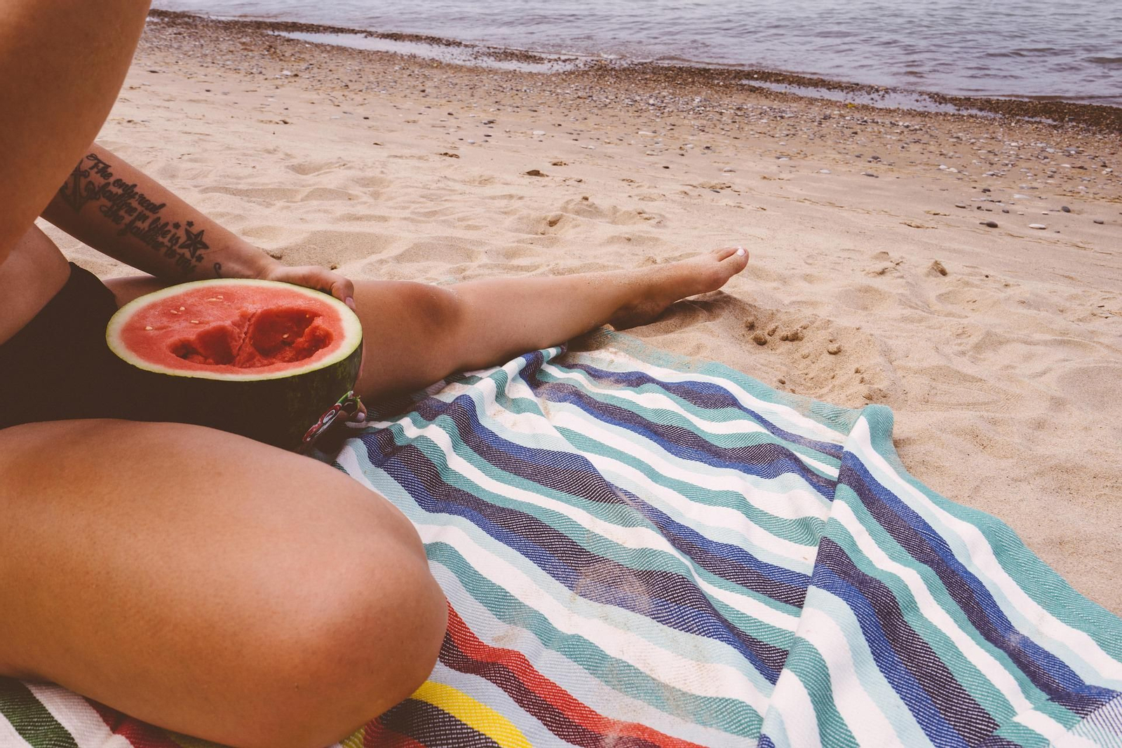 Una joven come sandía en la playa