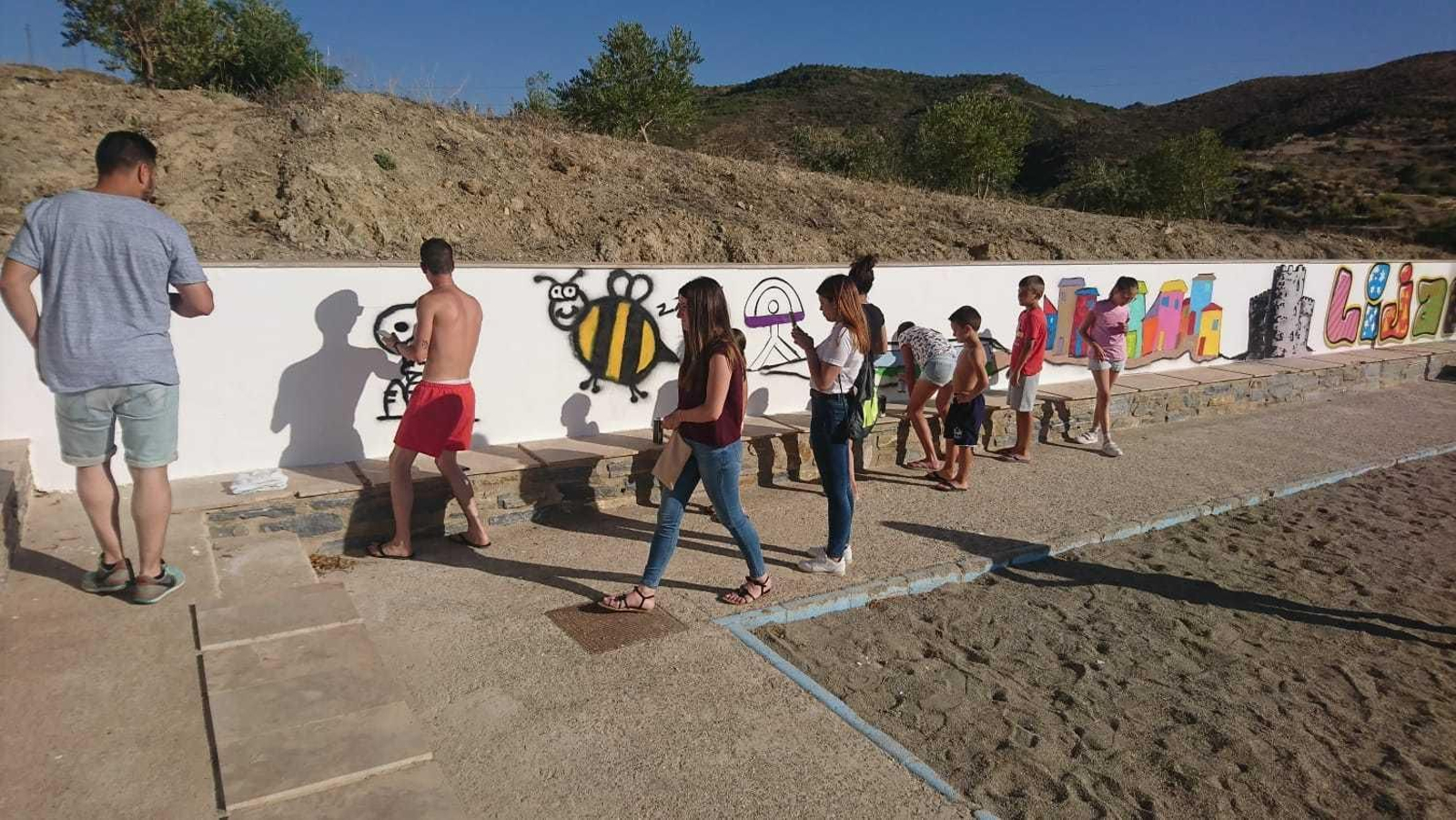 Participantes del taller pintando en los muros de la localidad poniendo a prueba sus conocimientos.