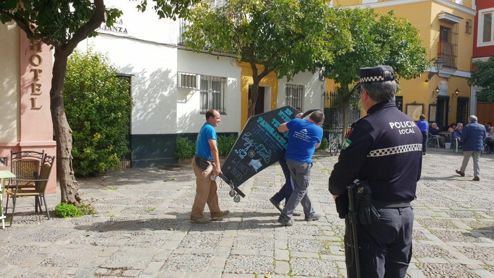 Tres operarios trasladan la cartelería de un negocio.