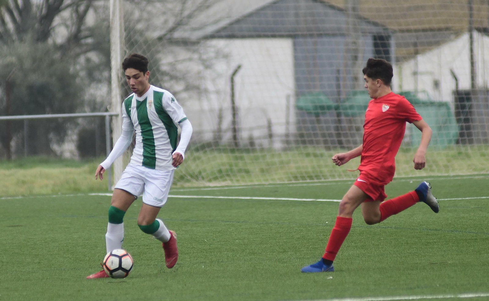 Un jugador del Córdoba controla el balón en presencia de un sevillista.