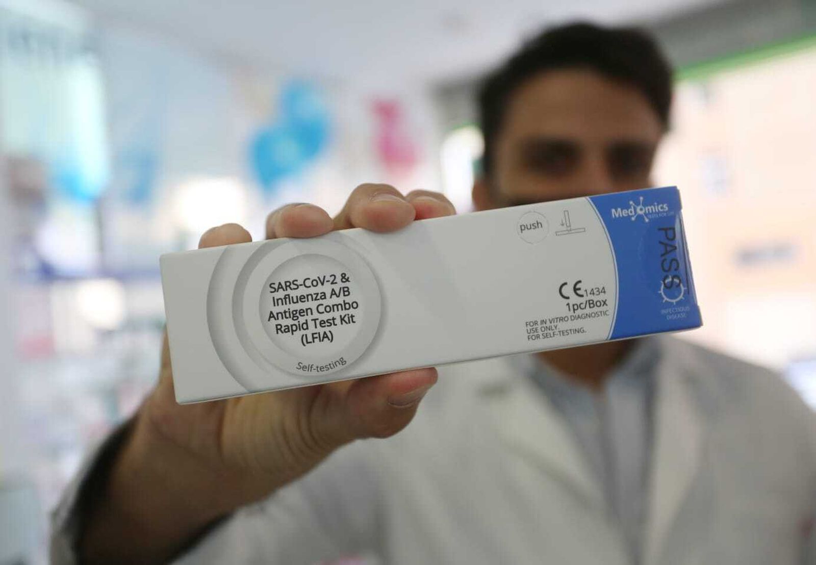 Un sanitario de la farmacia del barrio de La Roca, en Málaga capital, sostiene el nuevo test combinado de gripe y Covid.