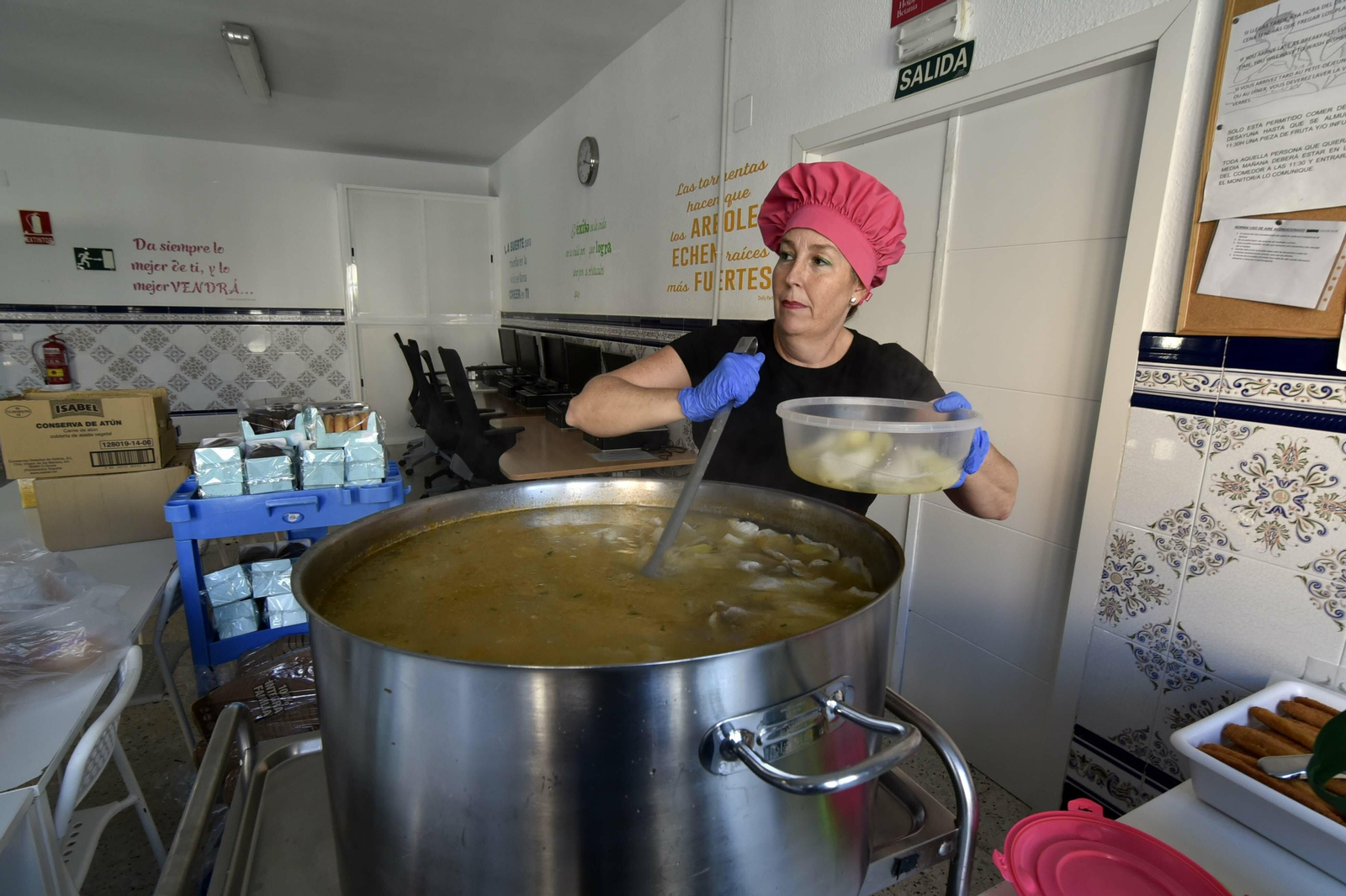 Yolanda López, una de las cocineras de Nuevo Hogar Betania, llena una fiambrera con sopa de pescado.