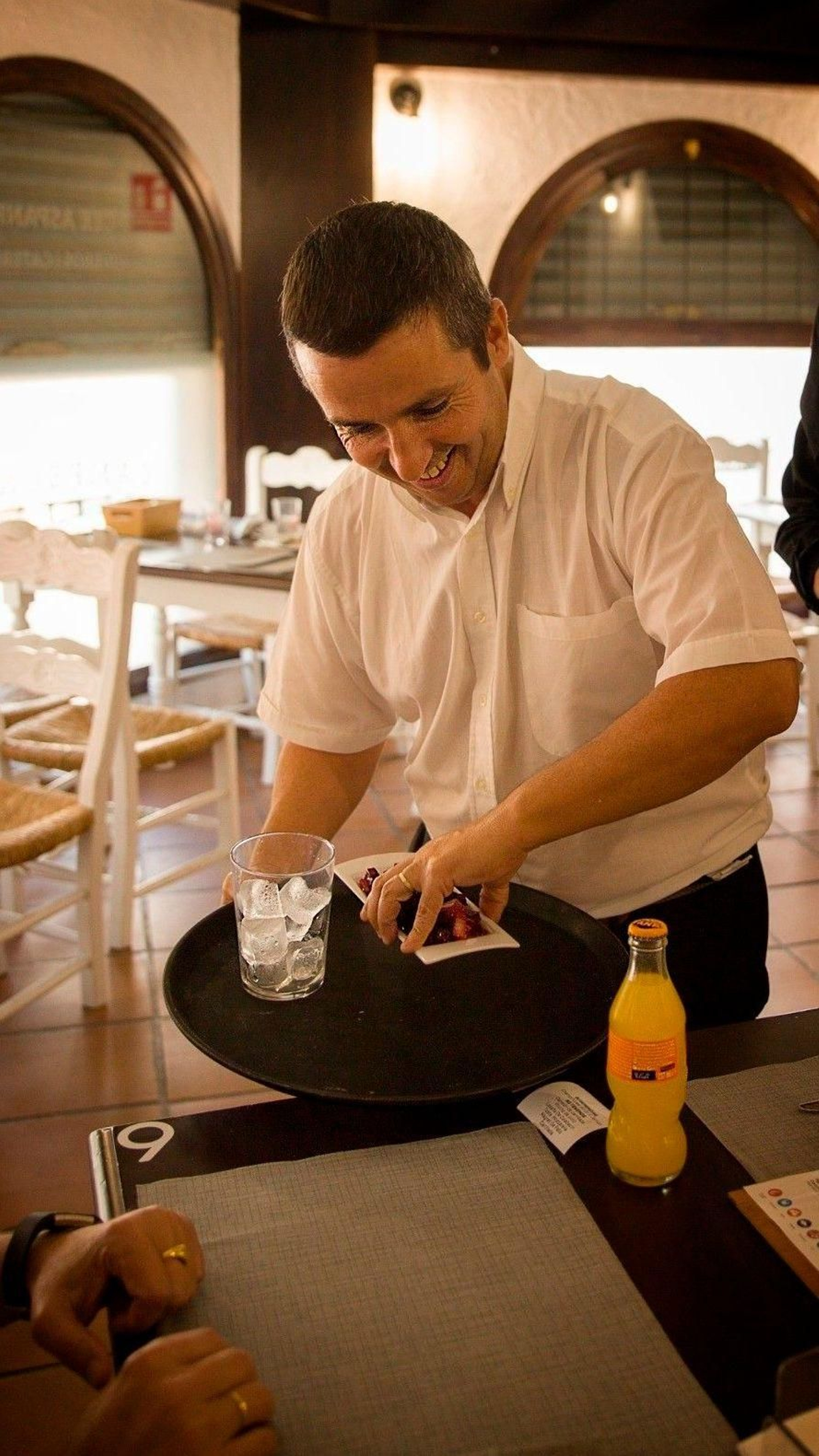 Un camarero con discapacidad intelectual atendiendo a una mesa del mesón 'Campeones' del barrio sevillano de Nervión.