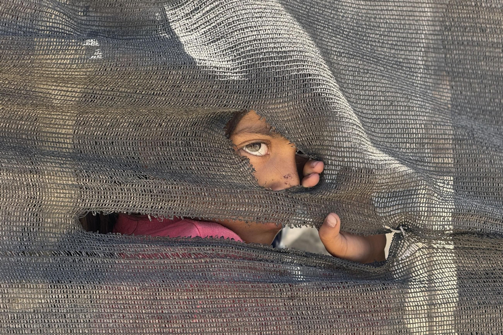 Una niña se asoma tras una tienda improvisada en el puerto en Ciudad de Gaza. Una niña se asoma tras una tienda improvisada en el puerto en Ciudad de Gaza.
