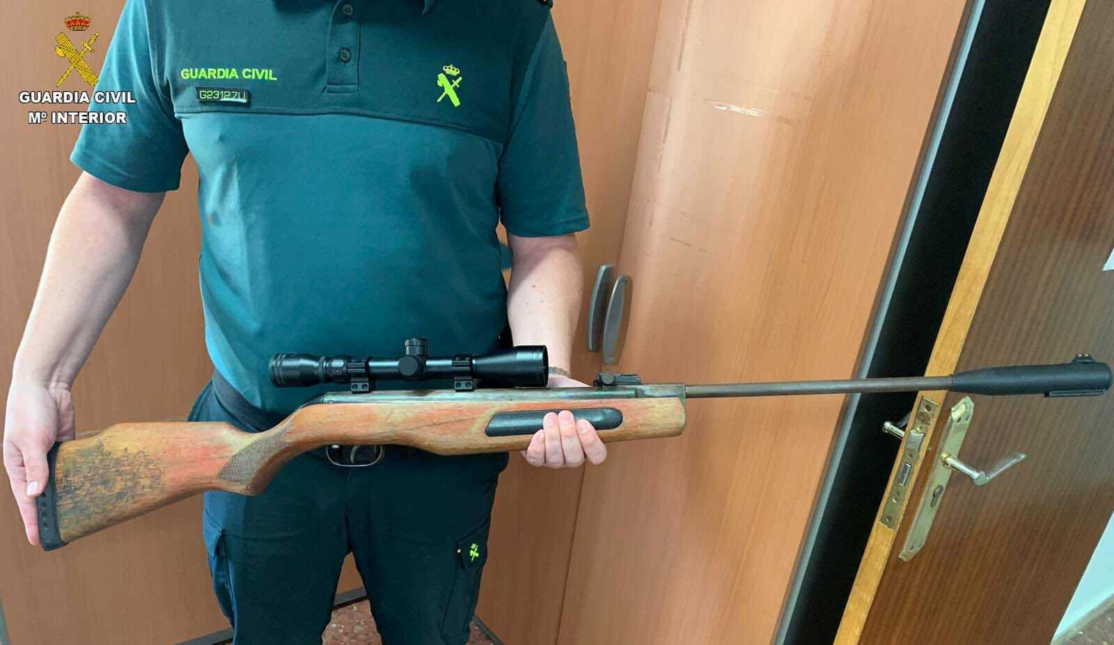 Un agente de la Guardia Civil porta el arma del investigado.