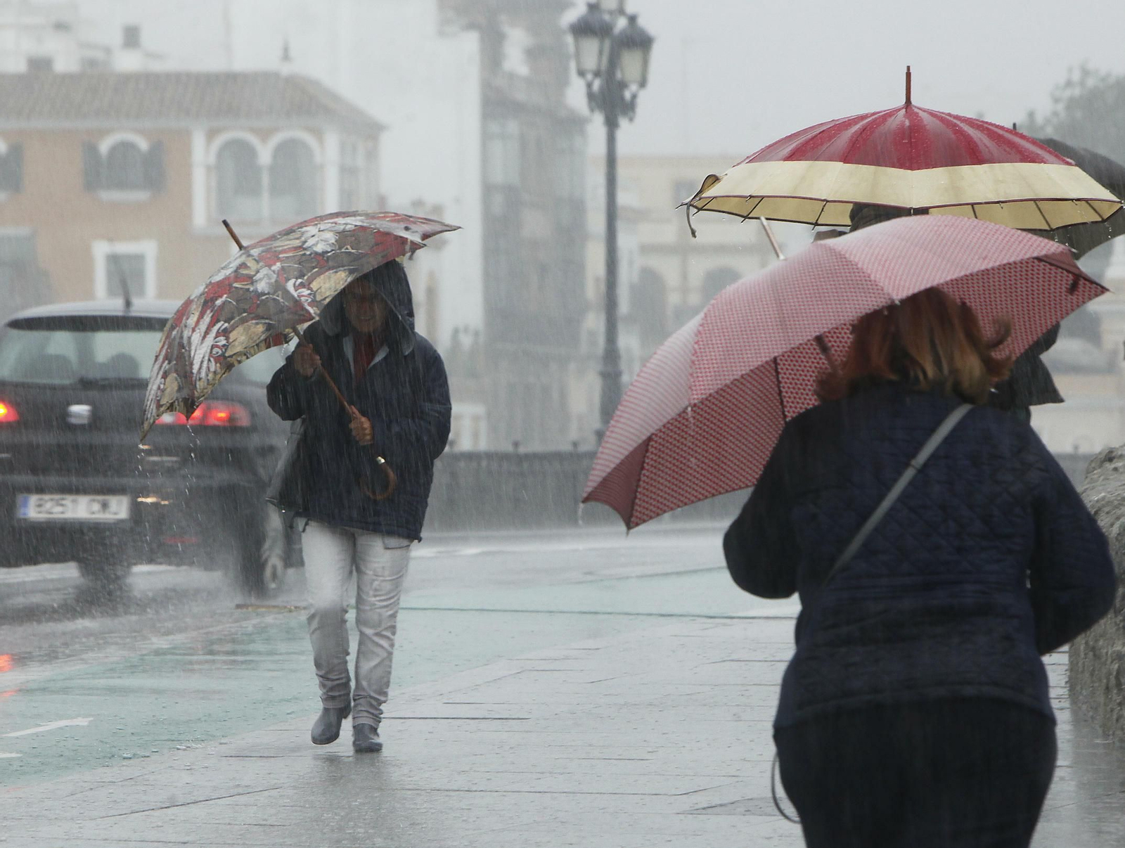 Varias personas intentan protegerse de la lluvia bajo sus paraguas