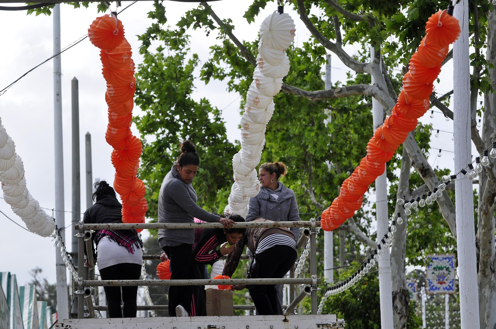 Mujeres colocando farolillos en el real de Los Remedios.