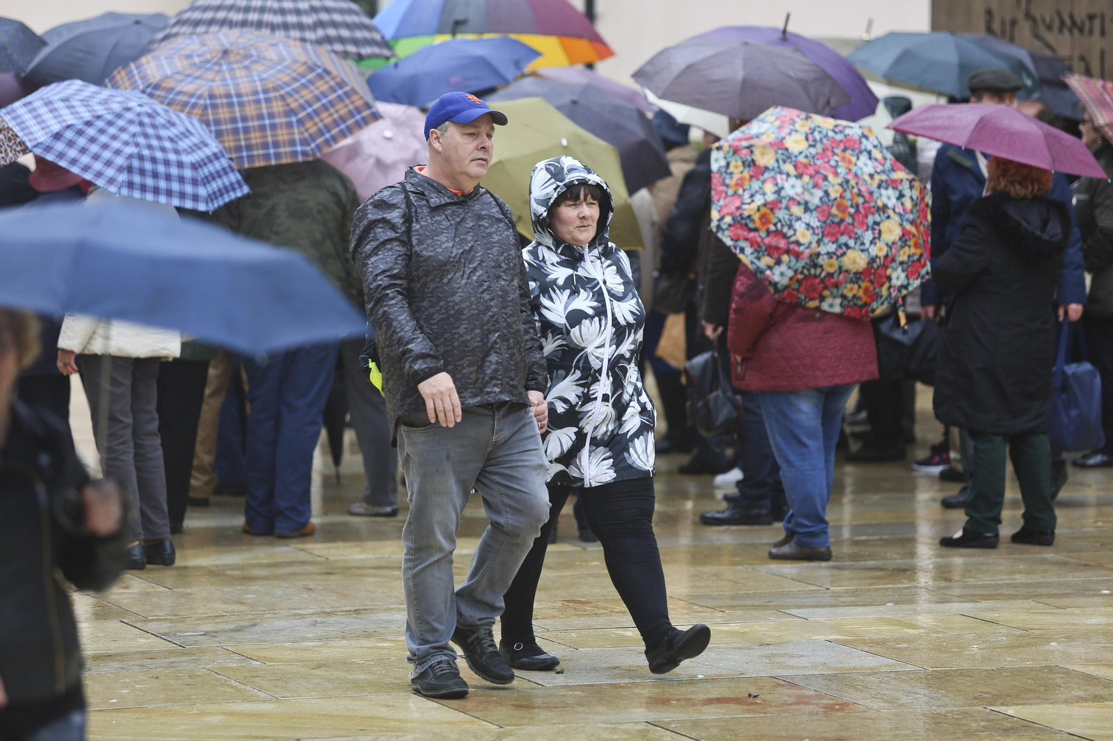 Dos personas paseando ayer con chubasqueros.