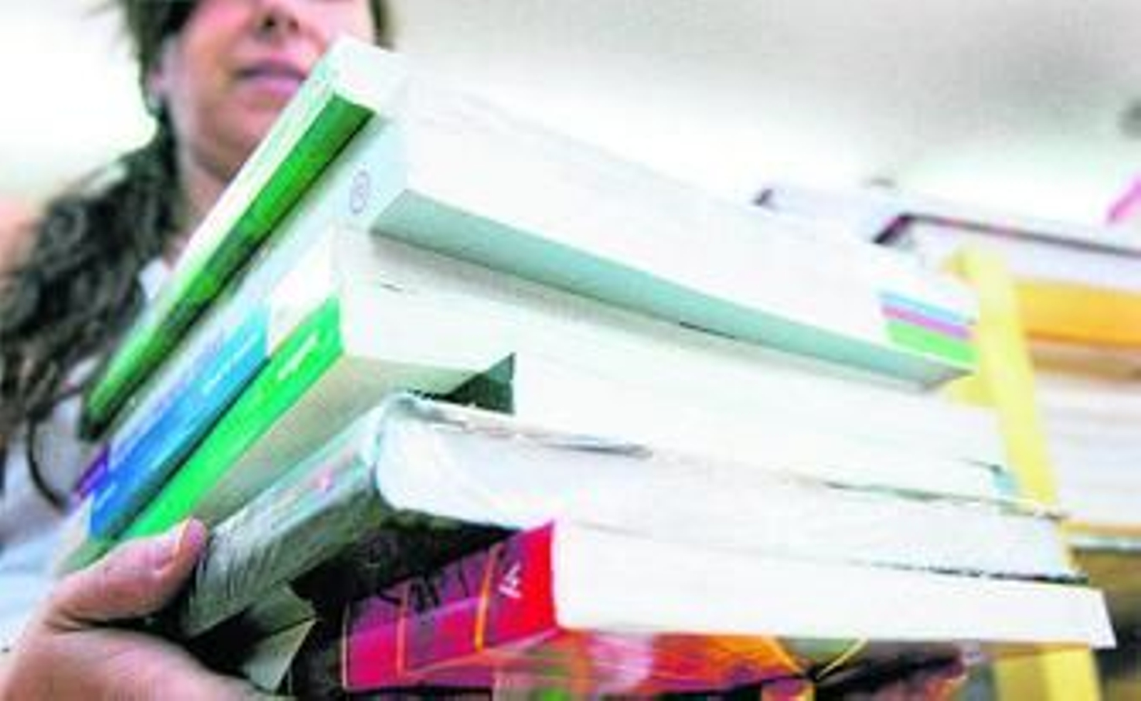 La empleada de una librería sostiene varios libros.