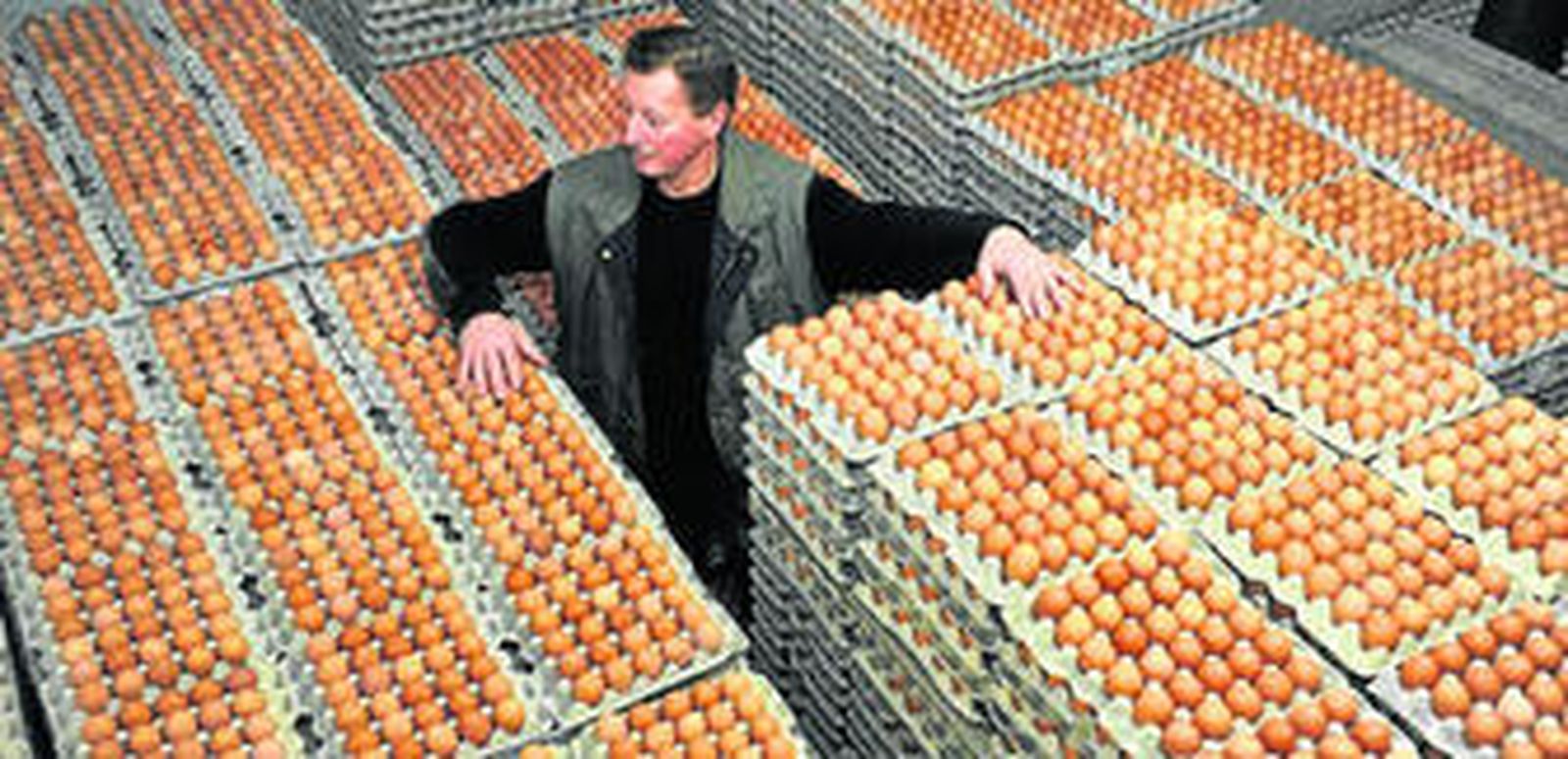 Un hombre muestra la mercancía de su granja cerrada por riesgo de contaminación, ayer en Alemania.