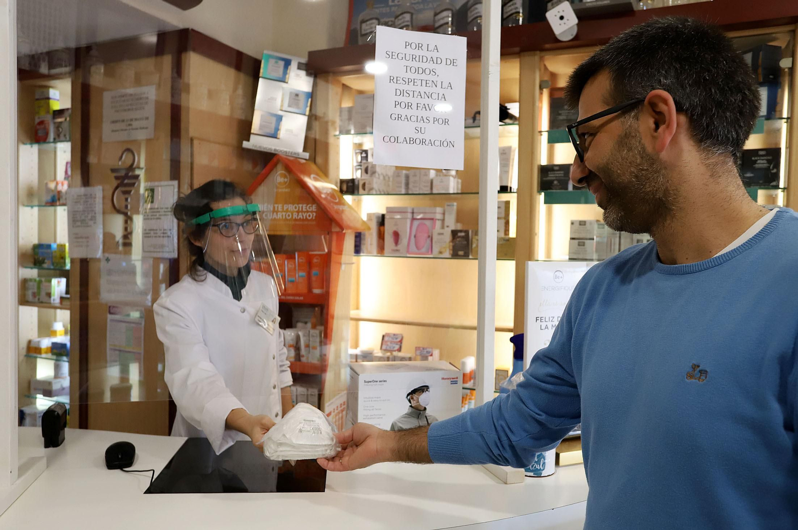 Una farmacéutica le entrega a un usuario mascarillas.