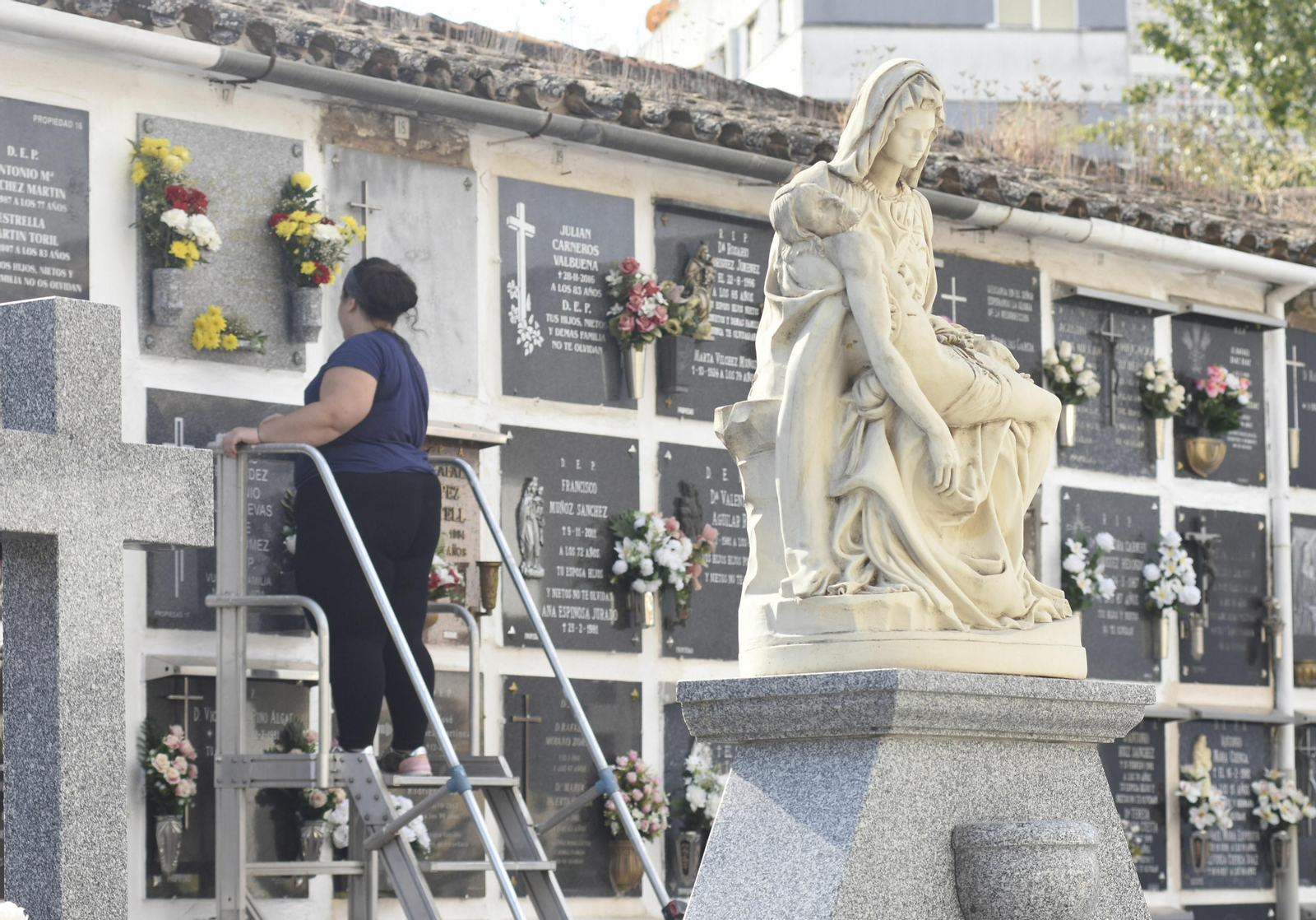 Una mujer limpia una lápida en el cementerio de San Rafael
