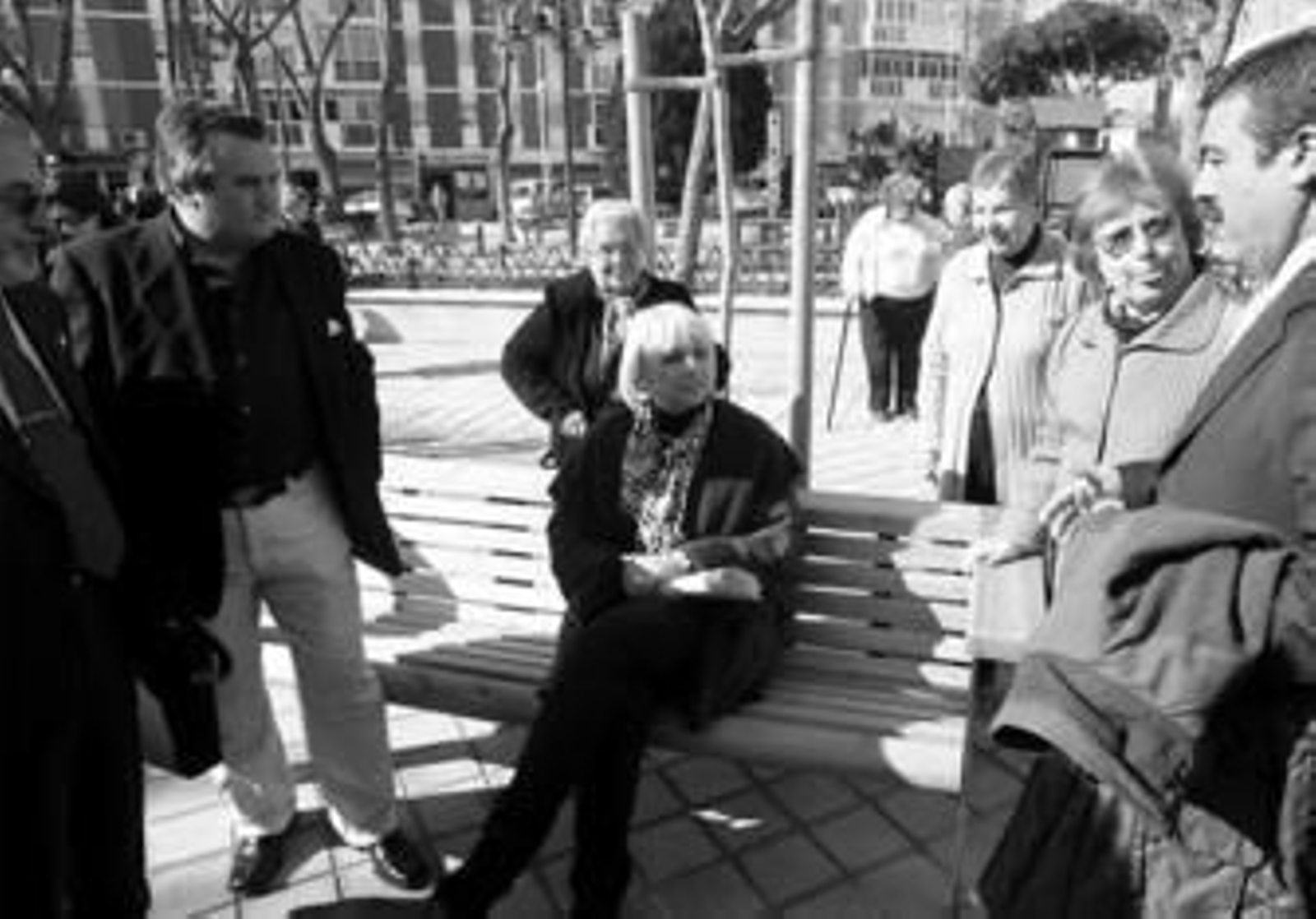 La alcaldesa, rodeada de vecinos, se sienta en uno de los bancos de la plaza.