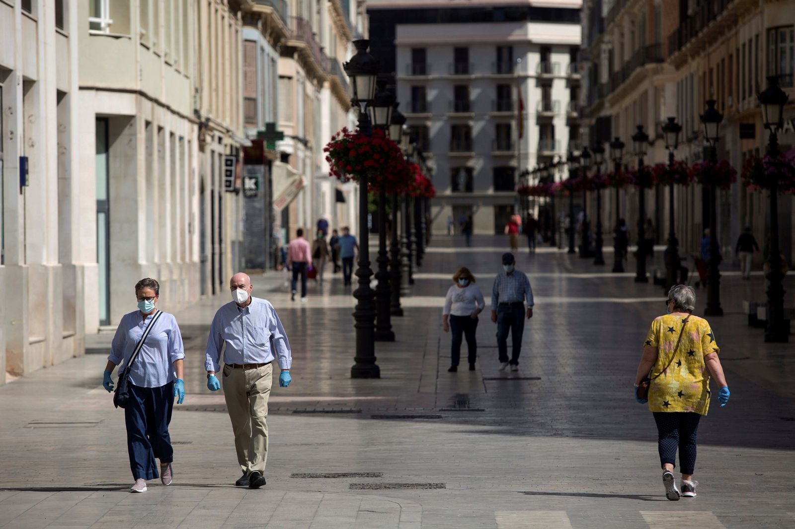 Varias personas pasean por la calle Larios de Málaga protegiéndose con mascarilla.