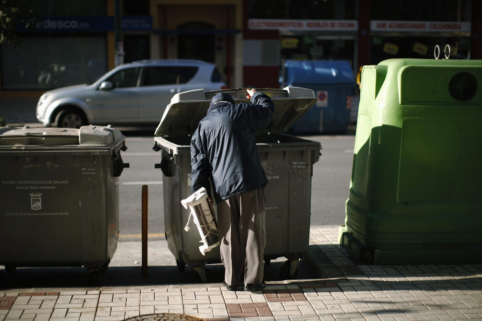 Un hombre busca cosas de valor en un contenedor de basura