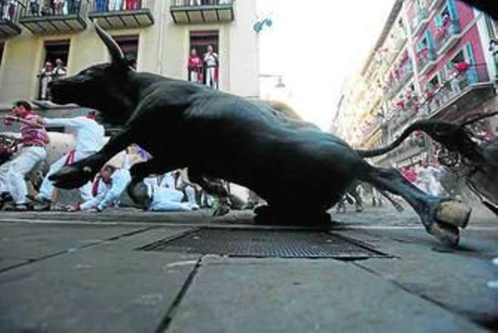 Un toro tras varios mozos en la curva de Mercaderes.