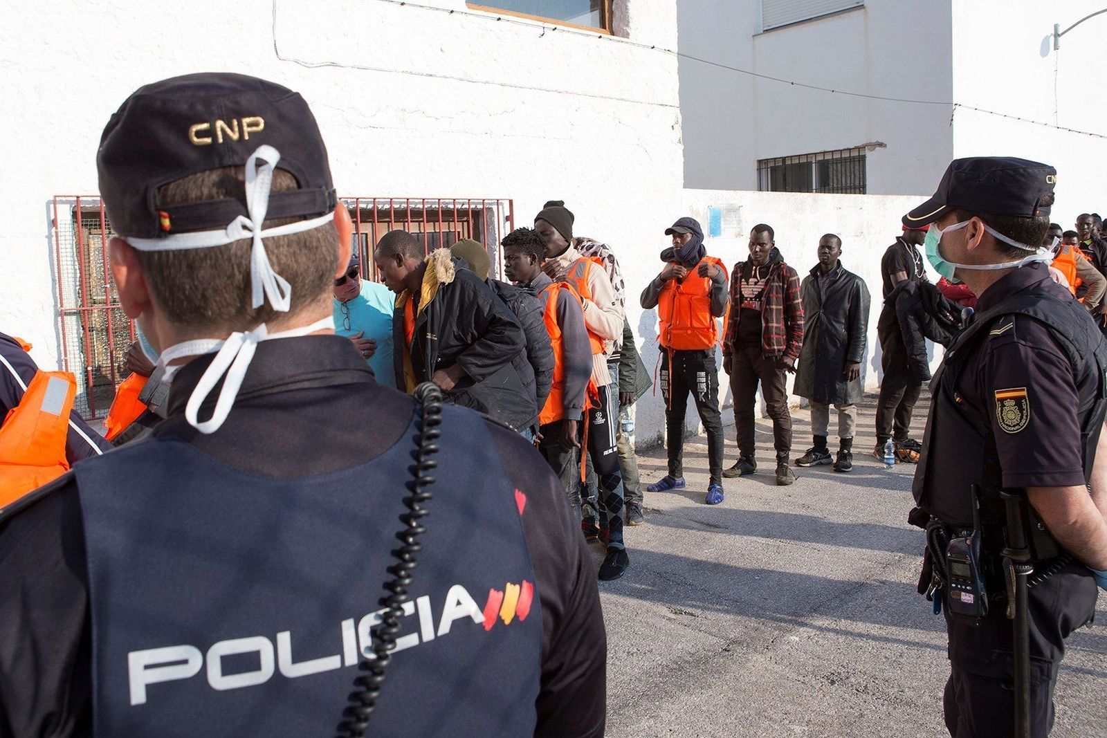 Agentes de Policía Nacional atienden a inmigrantes rescatados en patera en el Puerto de Motril.