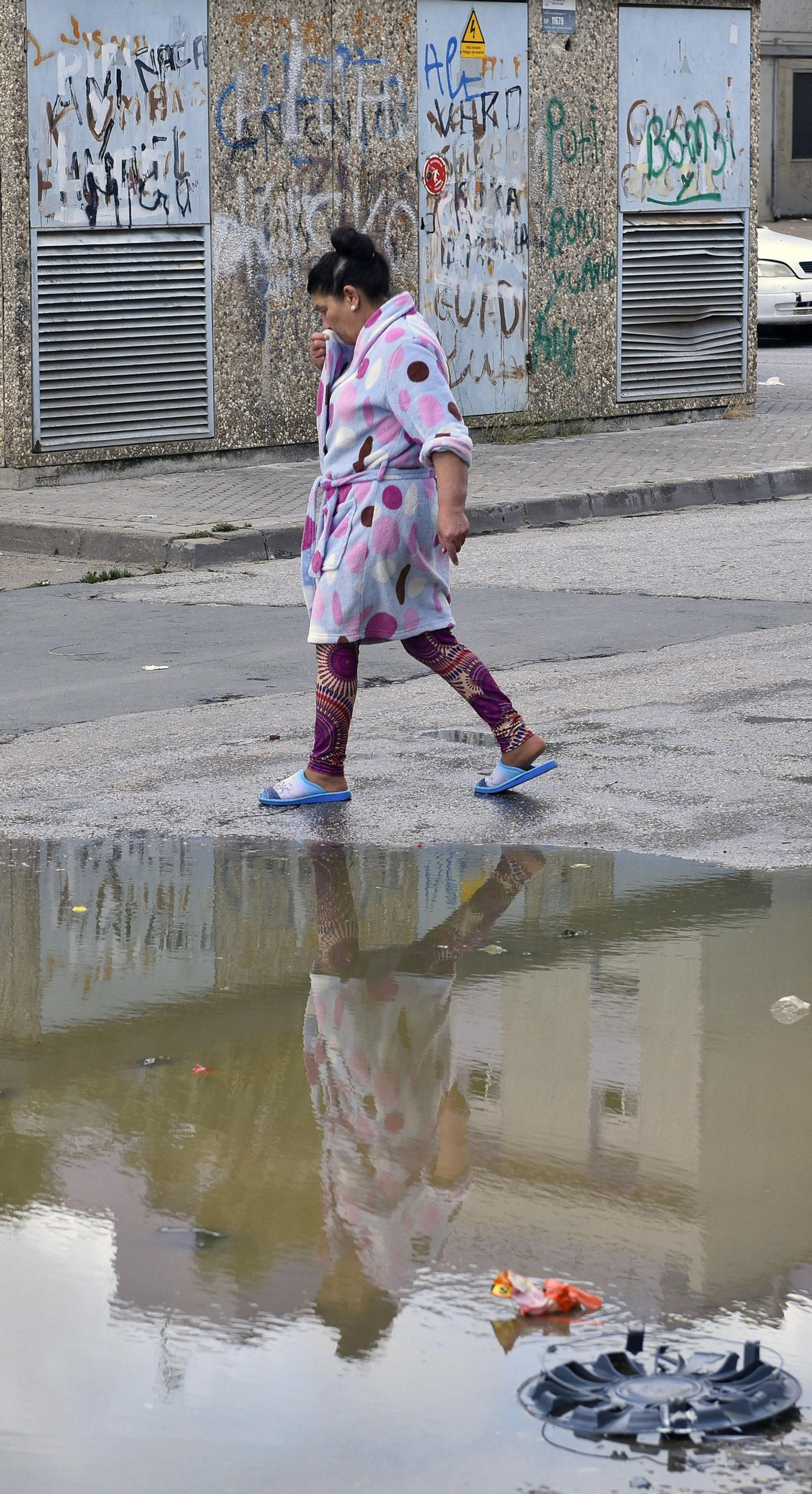 Una vecina se cubre la nariz ante el hedor del charco junto al que pasa.