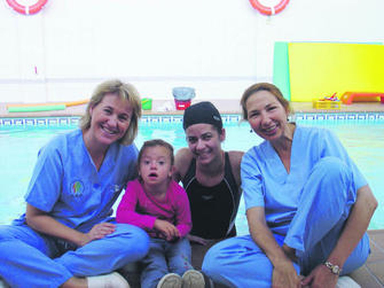 Personal del centro, con una niña, en la piscina.