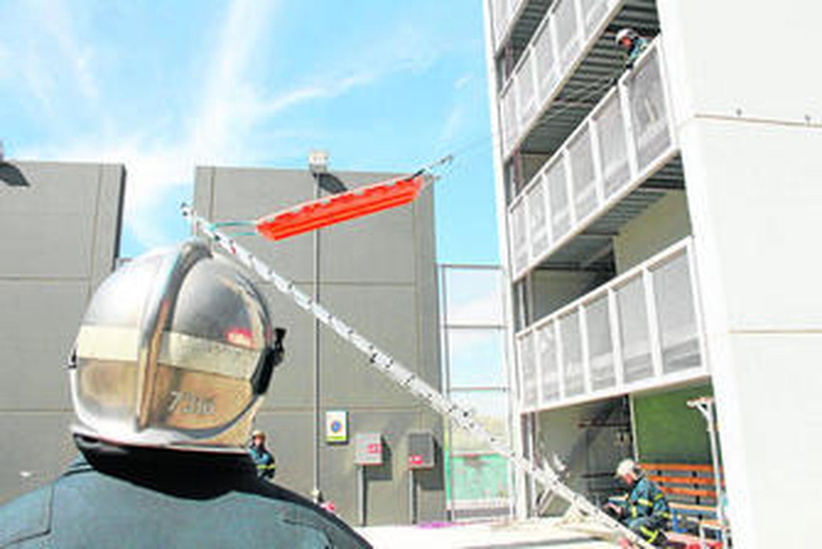 Momento en el que los bomberos participantes en el simulacro elevan una camilla a través de una escala para rescatar a un accidentado.