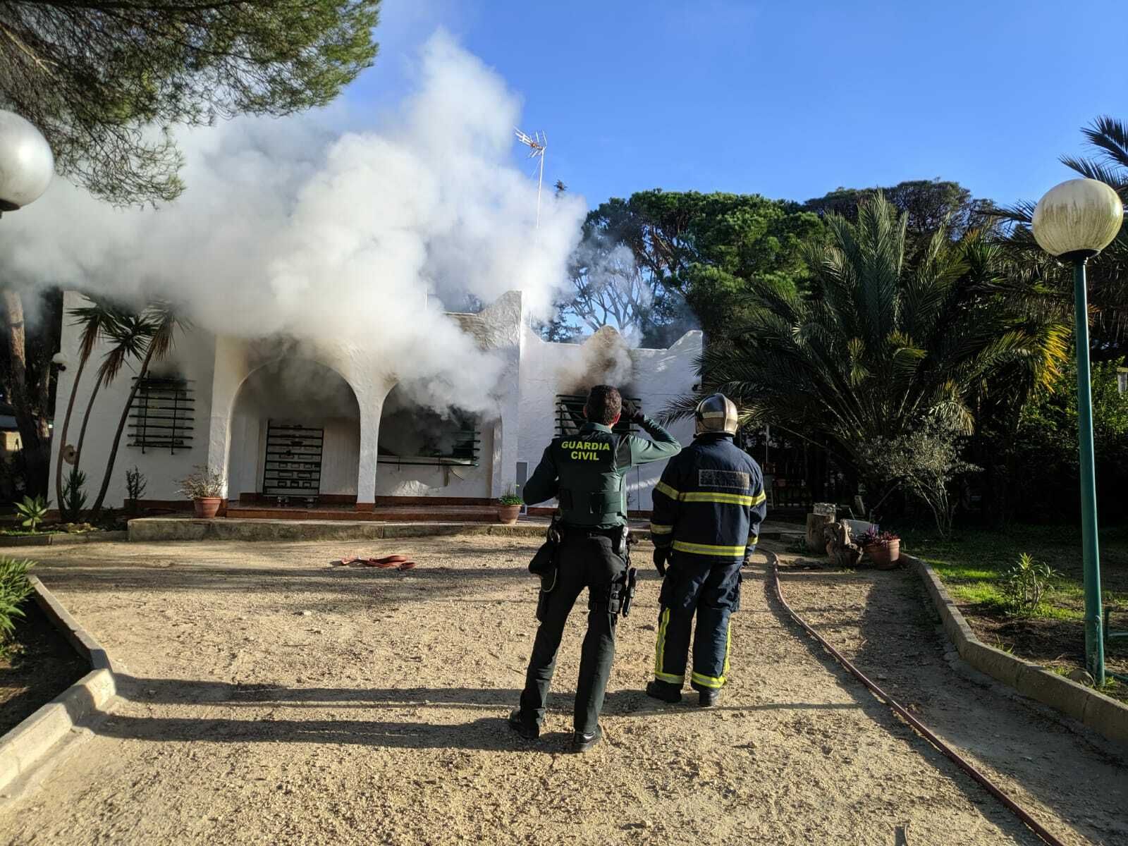 Un guardia civil y un bombero frente al chalet de La Barrosa durante el incendio.