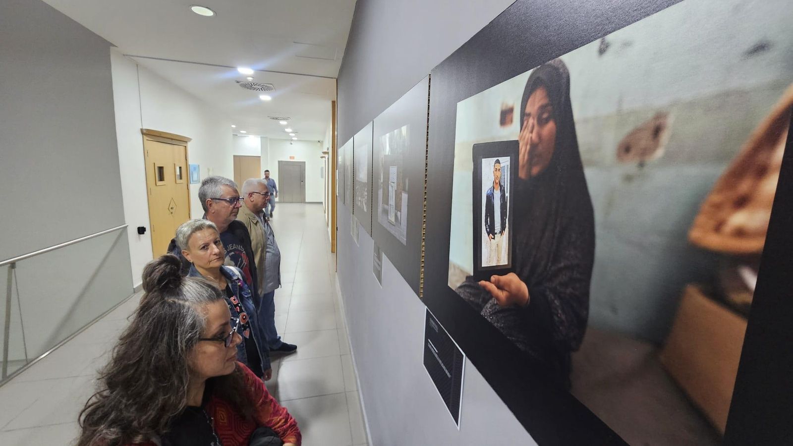 Parte del público mira las fotos de la exposición sobre Palestina en el Palacio de Congresos de La Línea.