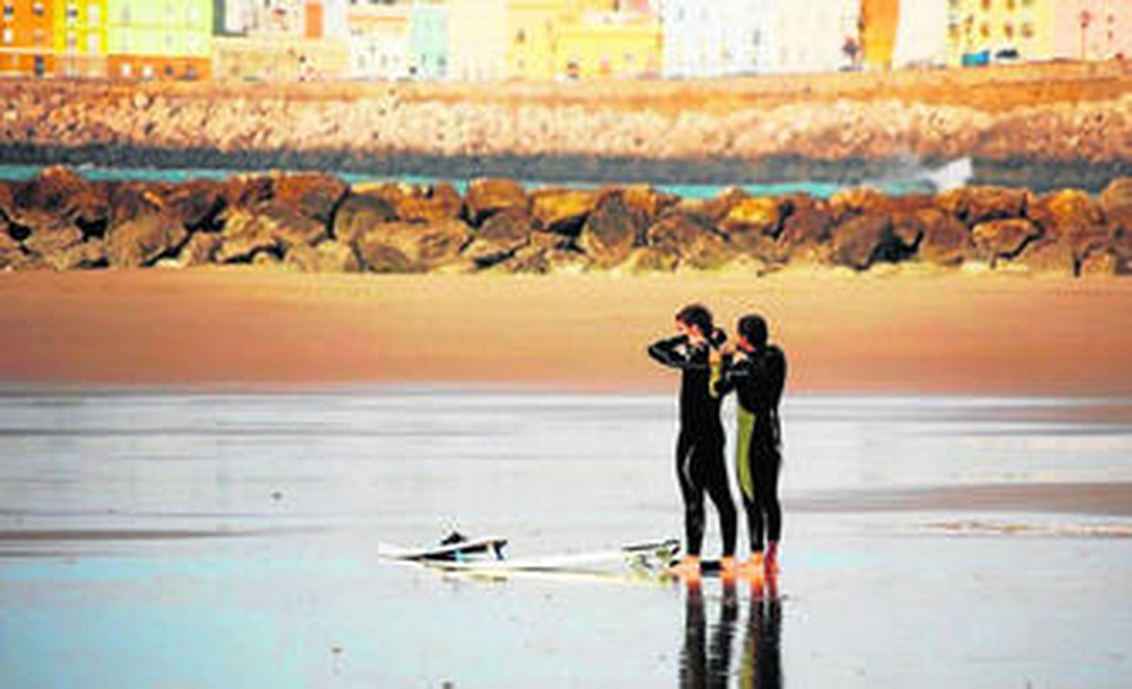 Dos jóvenes surfistas se preparan antes de entrar al agua en la Playa de Santa María del Mar.