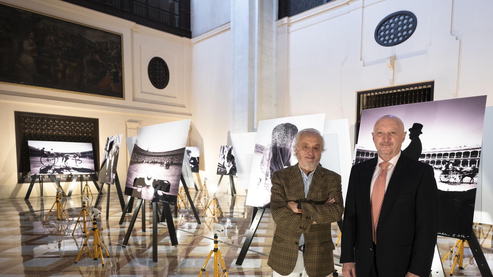 Los notarios Ramón Corrales y Manuel Seda junto a imágenes de la muestra.