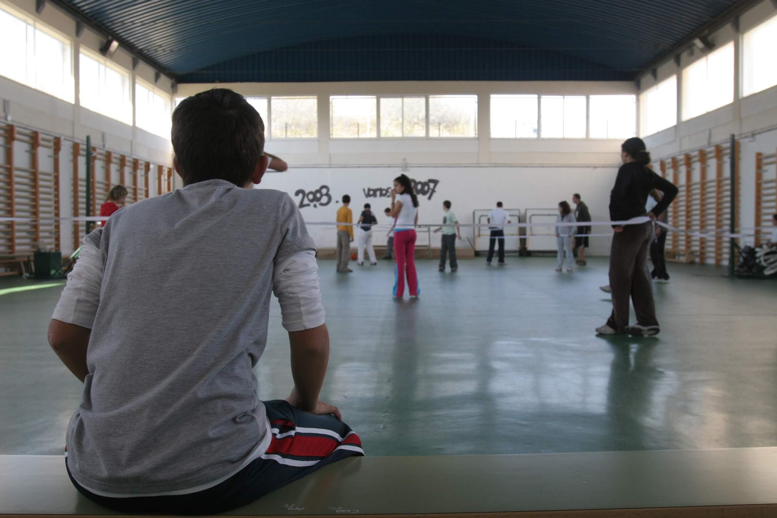 Un adolecente mira a sus compañeros mientras juegan.