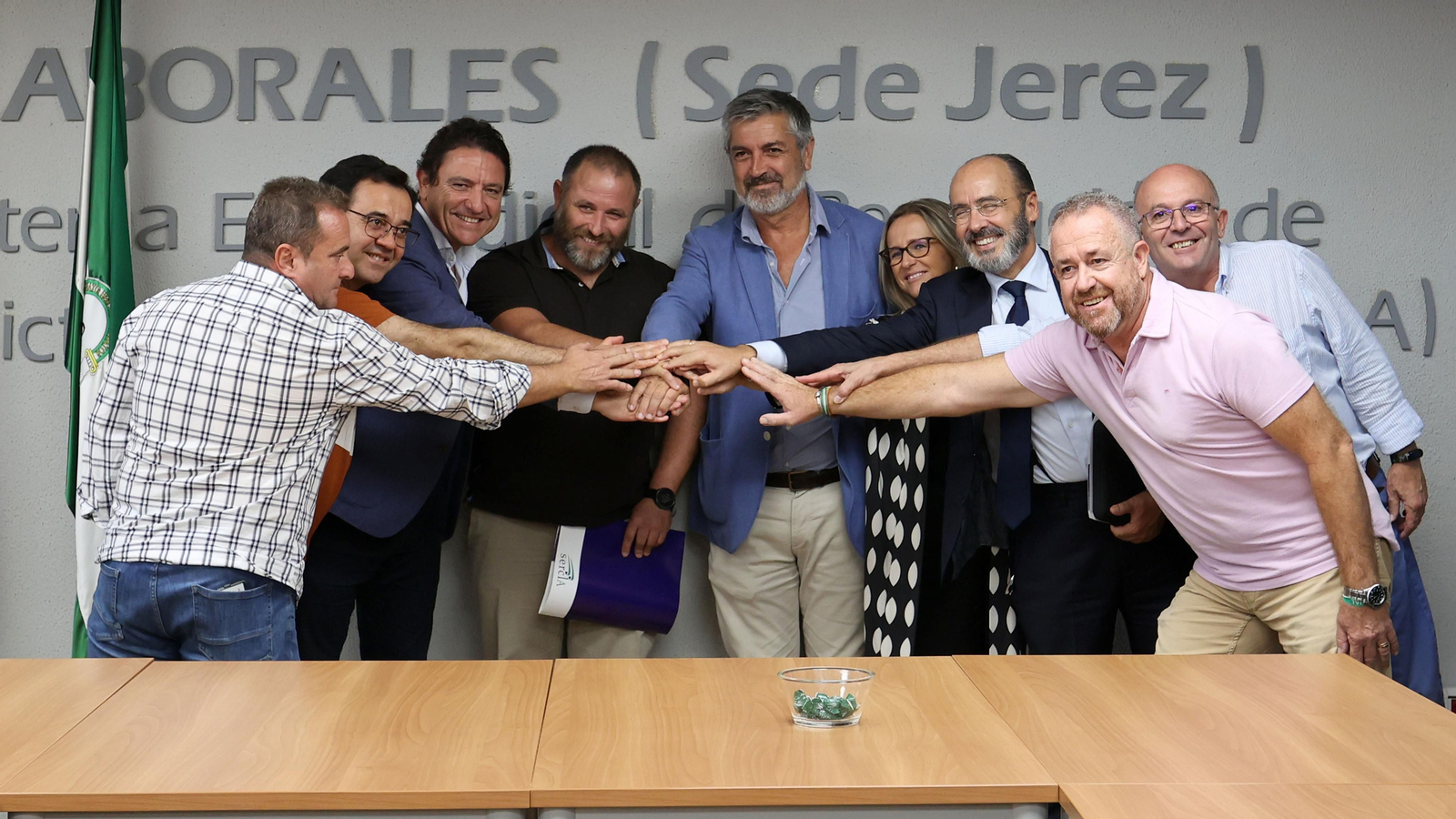 Representantes sindicales y de la patronal bodeguera juntan las manos con el delegado Territorial de Empleo tras la firma del acuerdo en el Sercla.