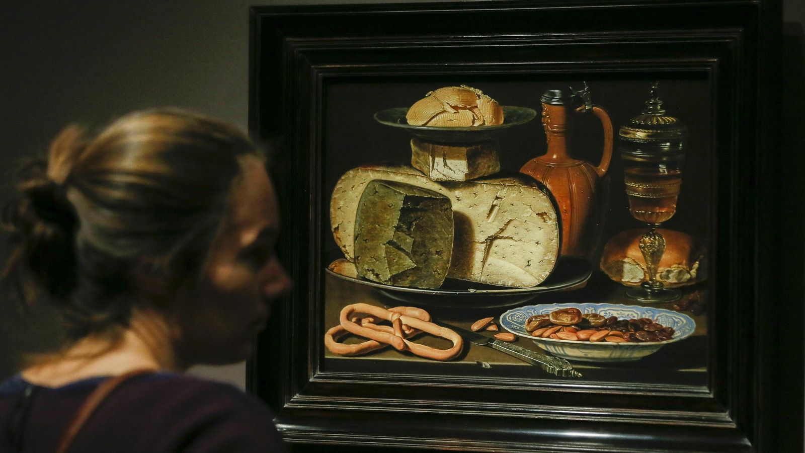 Una mujer observa la obra 'Bodegón con quesos, almendras y pretzels' en la muestra de Clara Peeters en el Prado.
