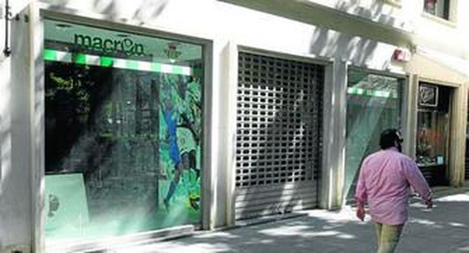 Un hombre camina junto a la fachada de la tienda del Real Betis en la Plaza Nueva, cerrada a finales de junio.