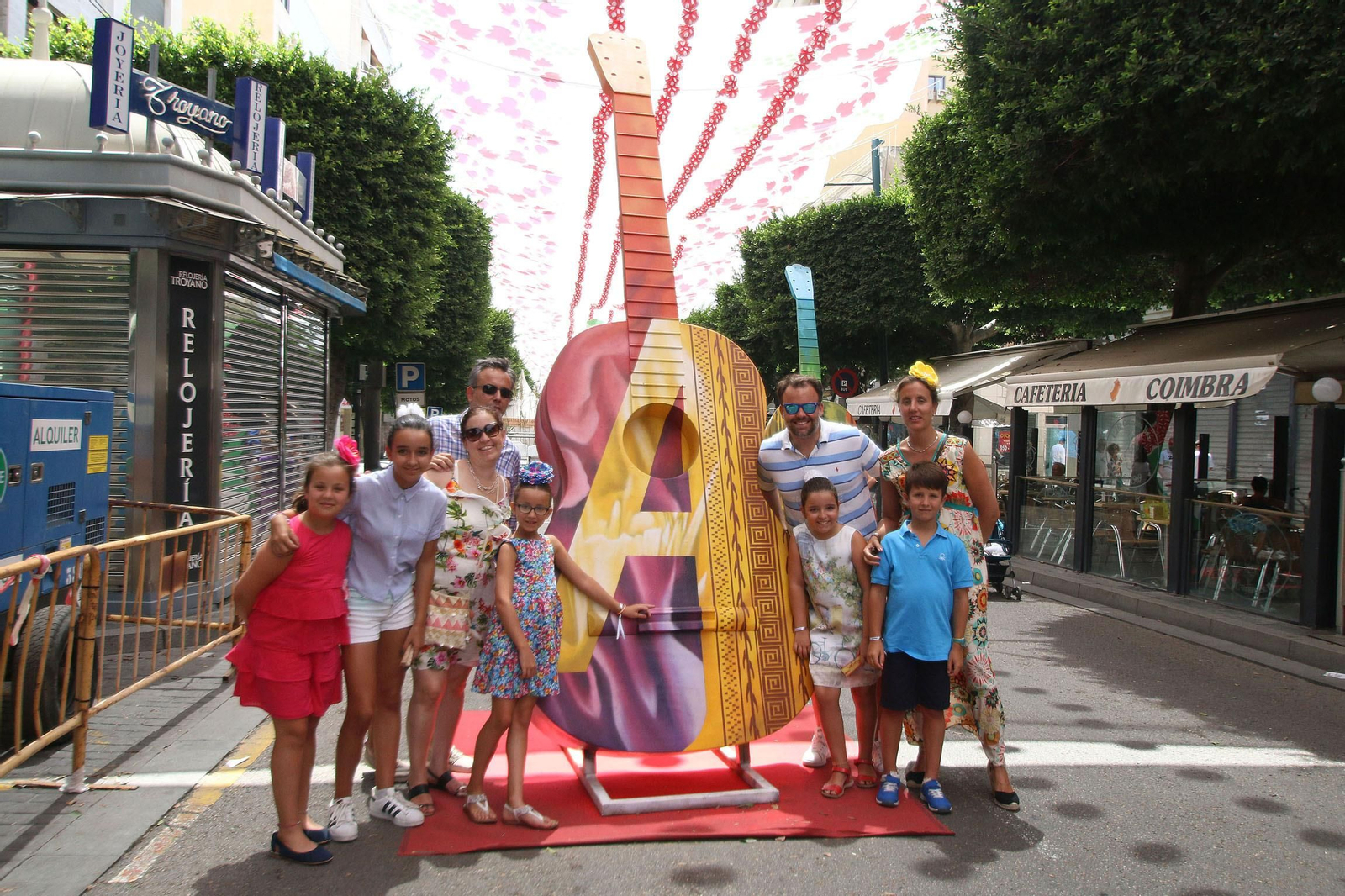 Una familia posando en las guitarras de colores que han puesto en El Paseo para la feria de Almería, en total hay seis guitarras diferentes.