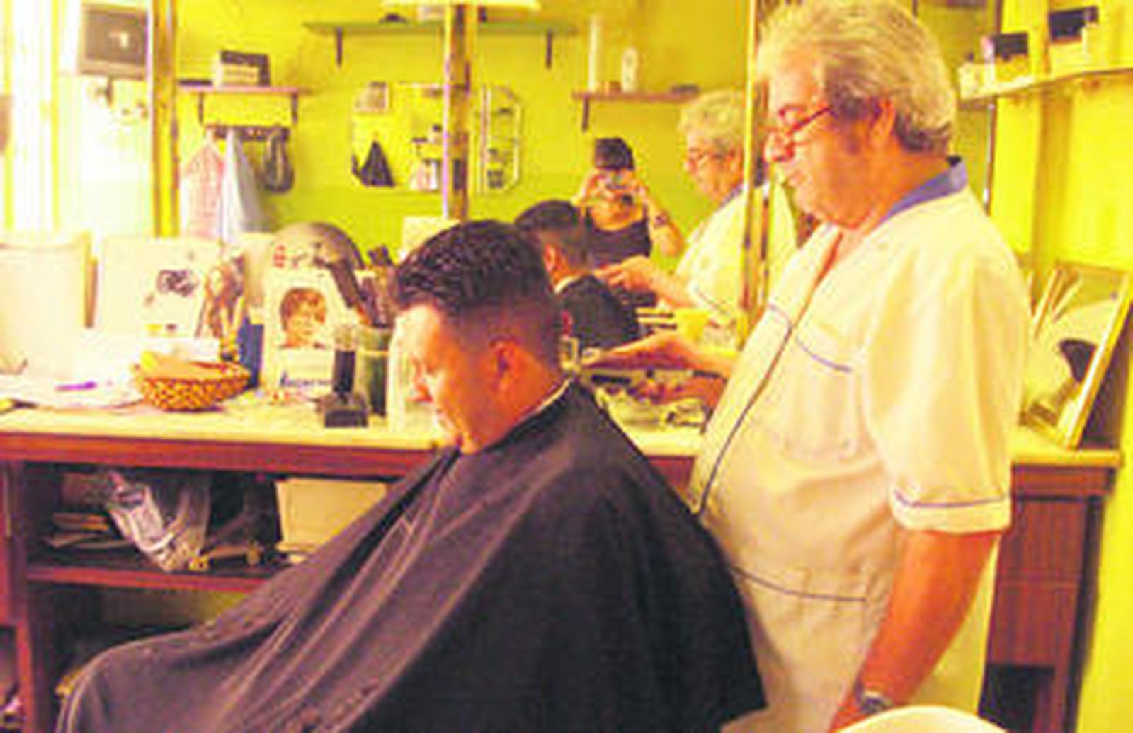 Juan Uclés, mientras peina a uno de sus clientes.